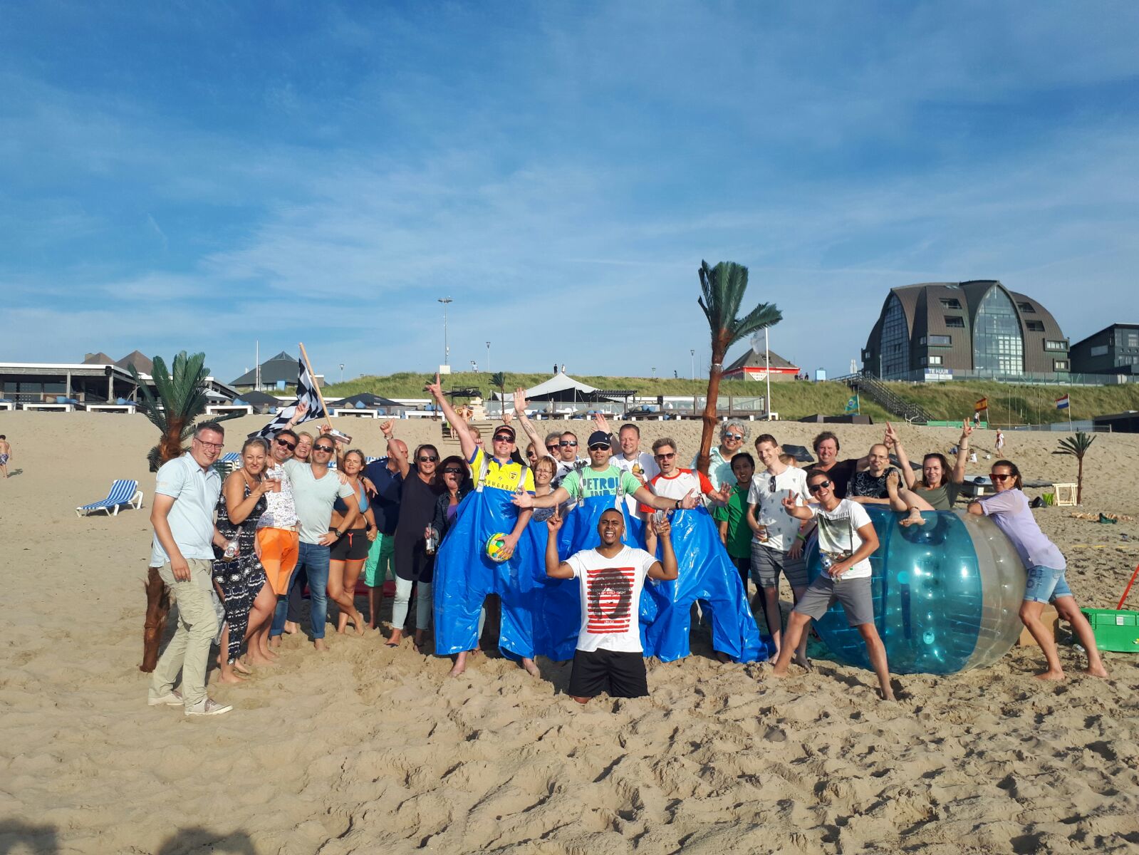 Groep collega's juicht op het strand na een teamspel