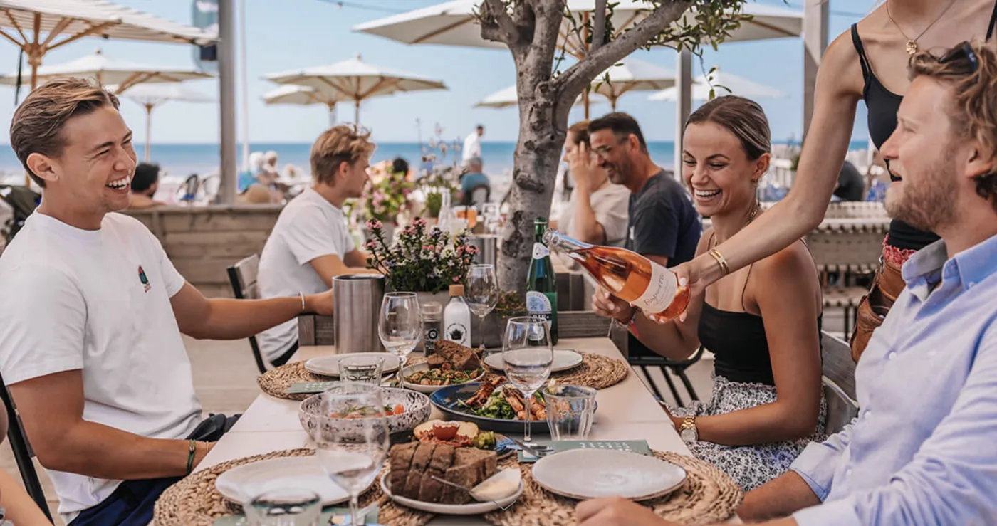 Collega's delen gerechten aan tafel op een terras aan zee